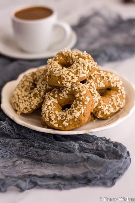 Sesame donuts on a plate with a cup of coffee, perfect for unique cookie recipes.