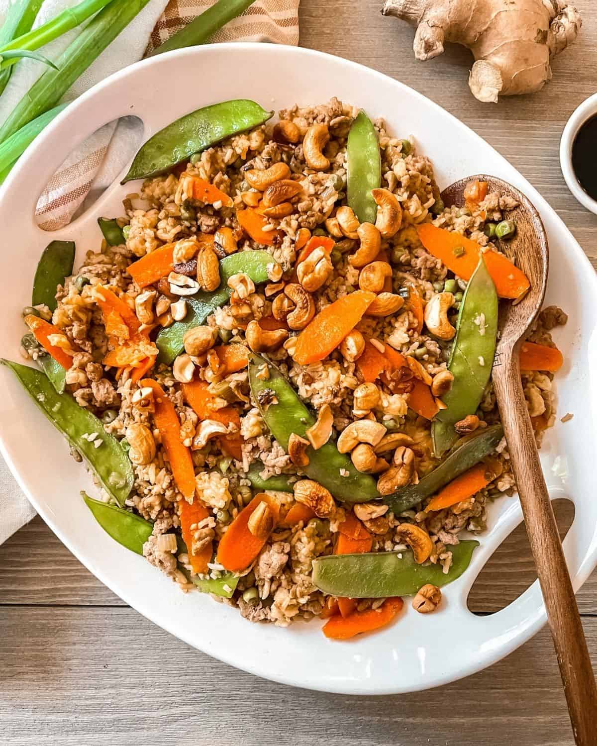 A white plate with carrots, cashews and peanuts.