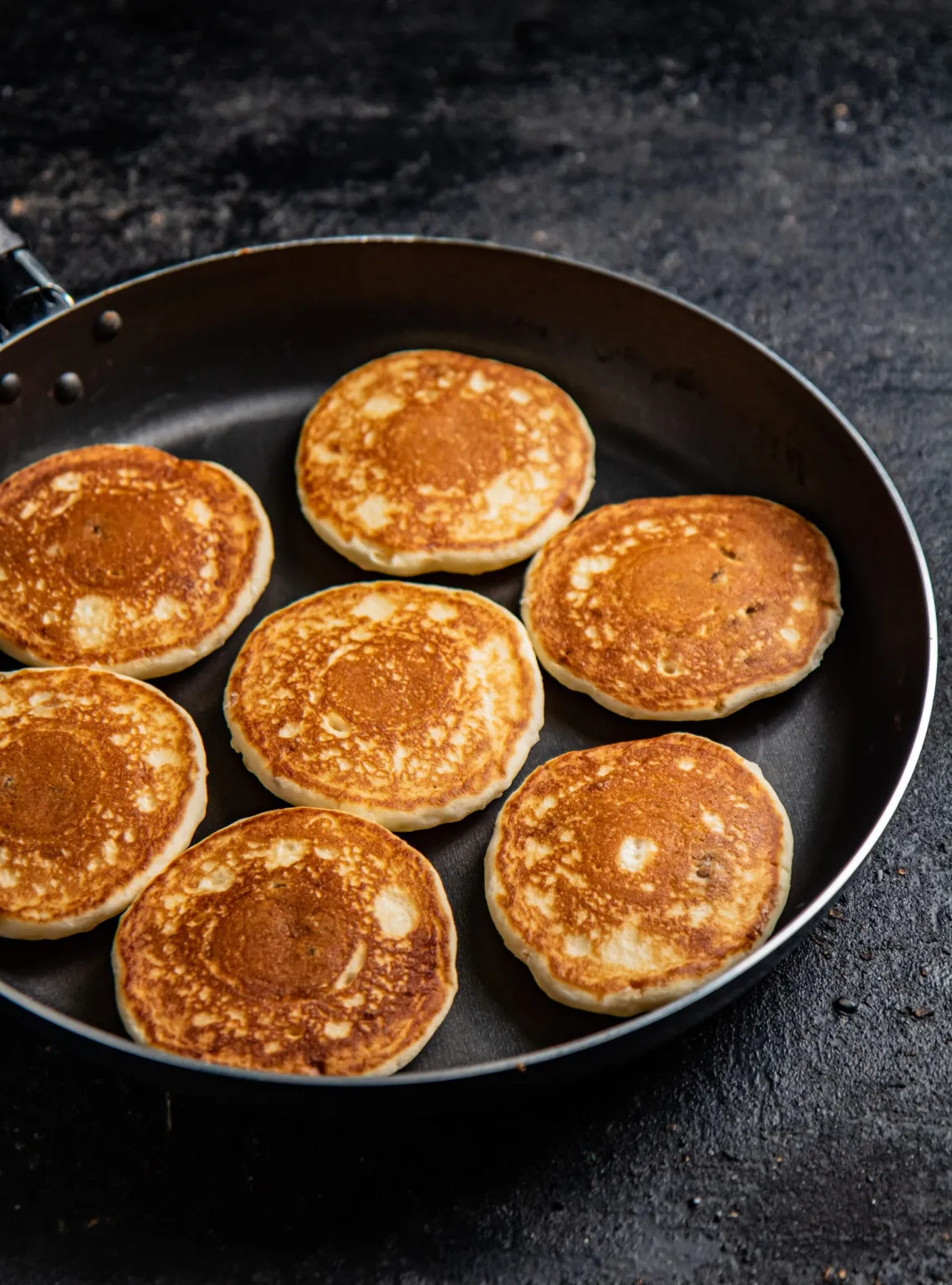 High protein pancakes in a frying pan on a dark background.