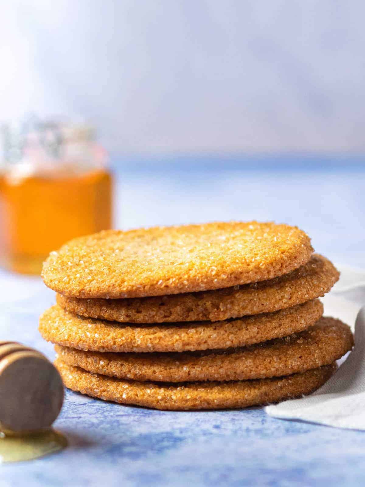A stack of unique cookies next to a bottle of honey.