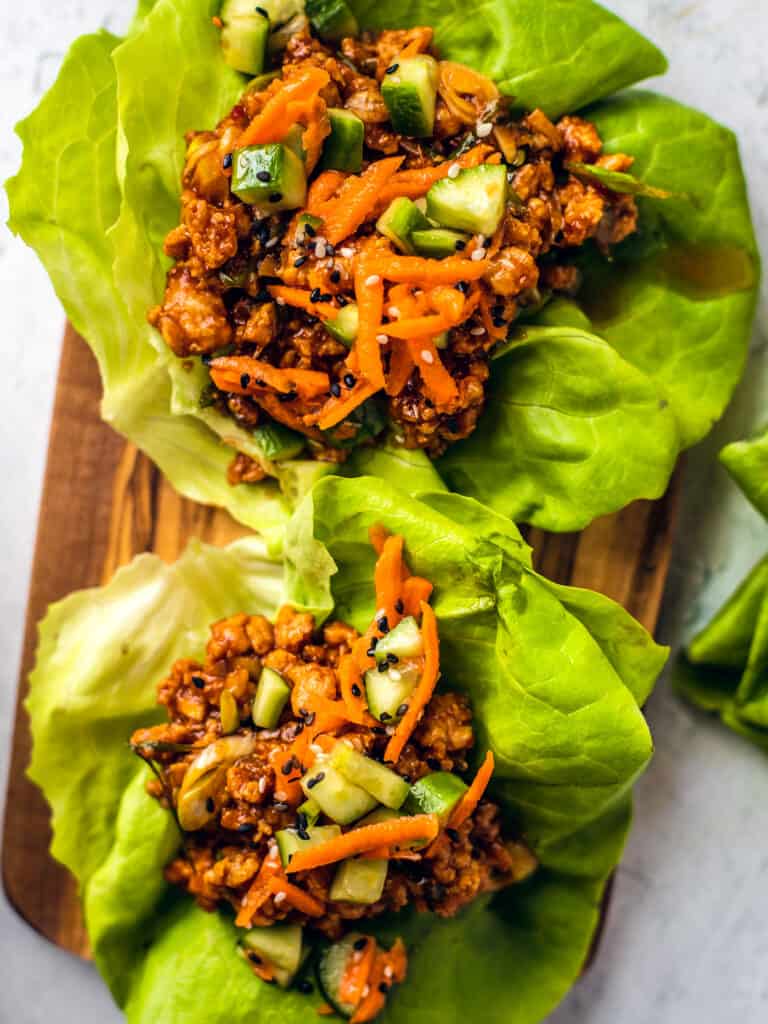 Close up of chicken lettuce wraps on a wooden serving board. 
