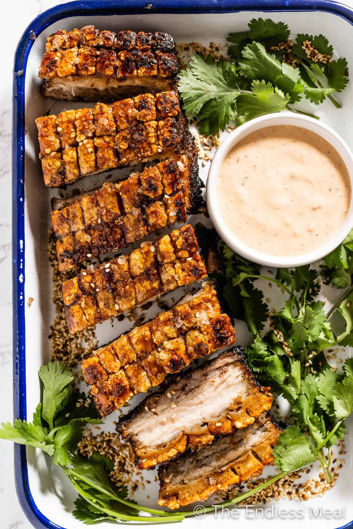 A plate of grilled ribs with a pork belly dipping sauce.