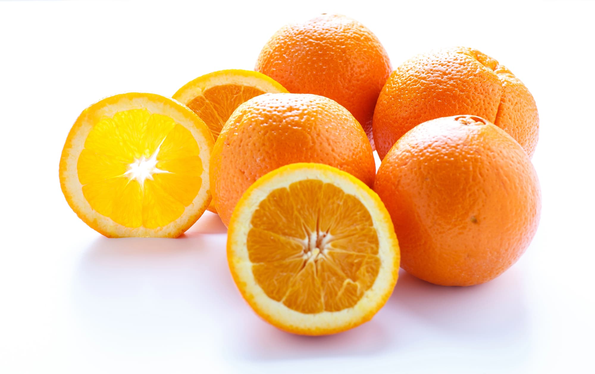 A bunch of nutritious oranges on a white surface.