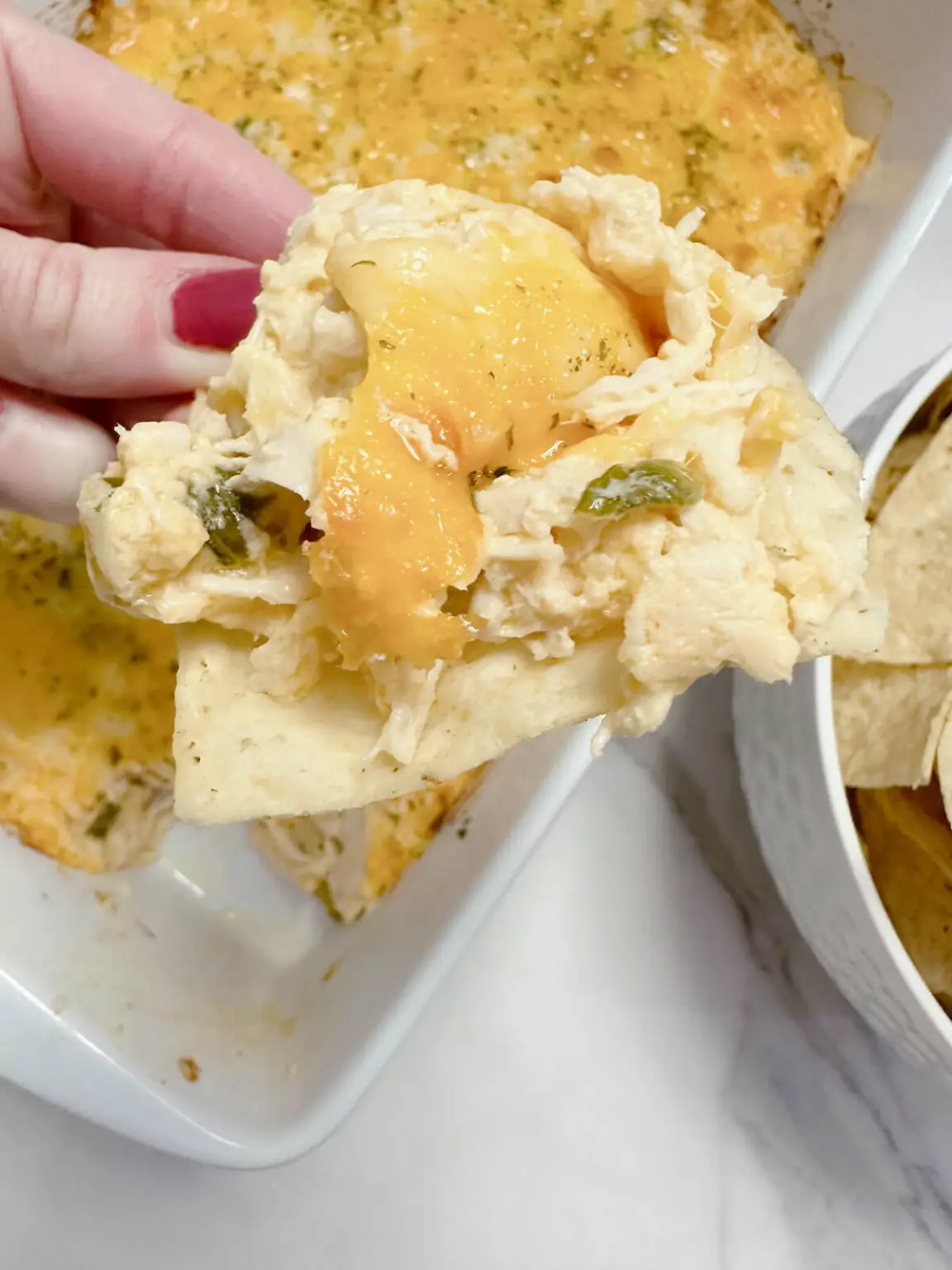 oven baked healthy buffalo chicken dip with greek yogurt scooped on a chip, ready to enjoy! 
