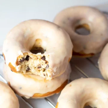 Unique donut flavors on a cooling rack with a bite taken out of them.