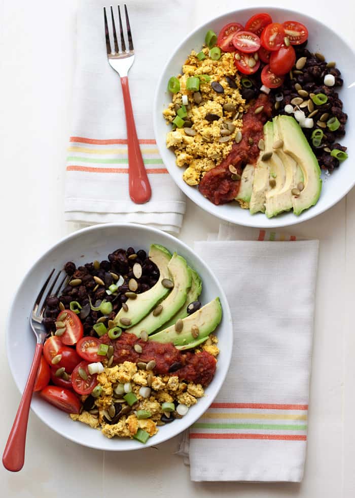 Two bowls with eggs, tomatoes and avocados on a napkin, perfect for a high protein breakfast.