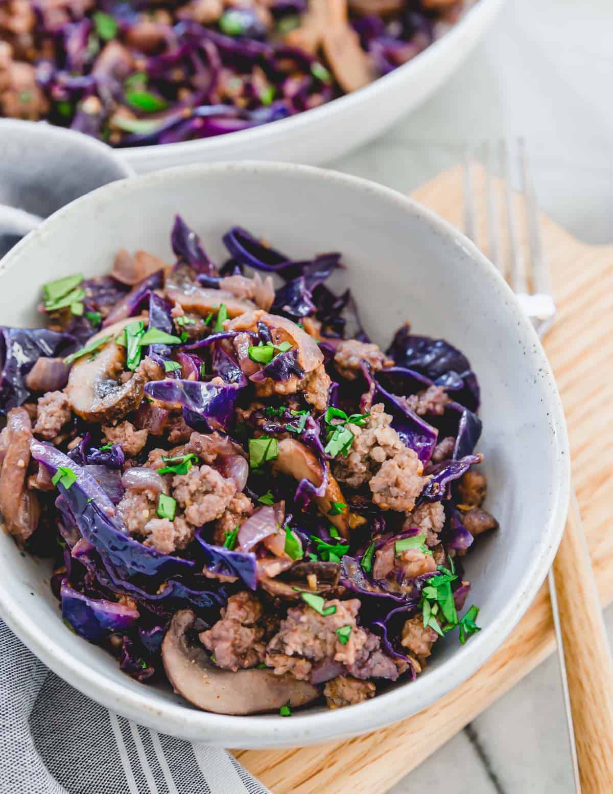 A bowl of red cabbage with meat and mushrooms.