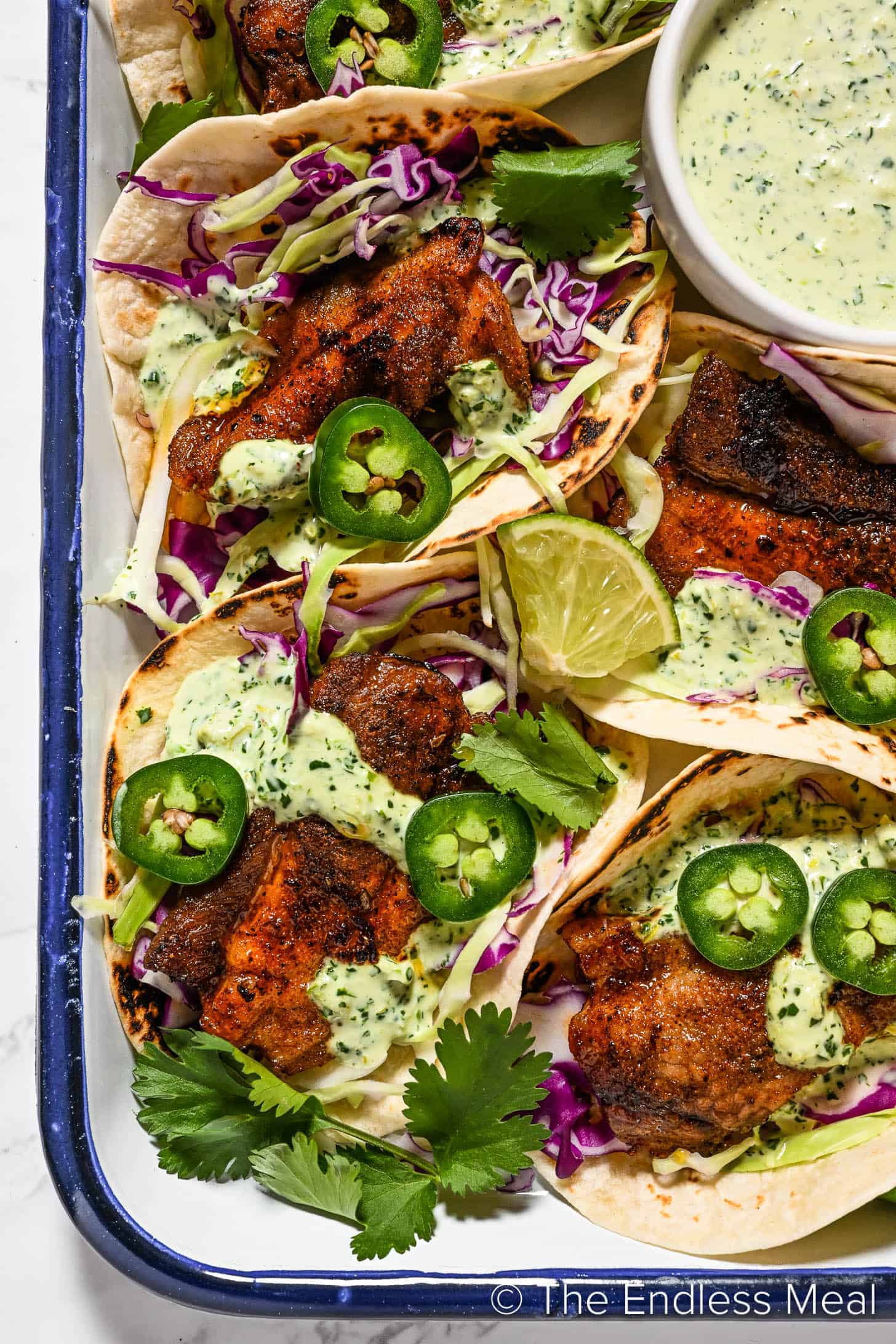 A tray of fish tacos with a tangy dipping sauce.