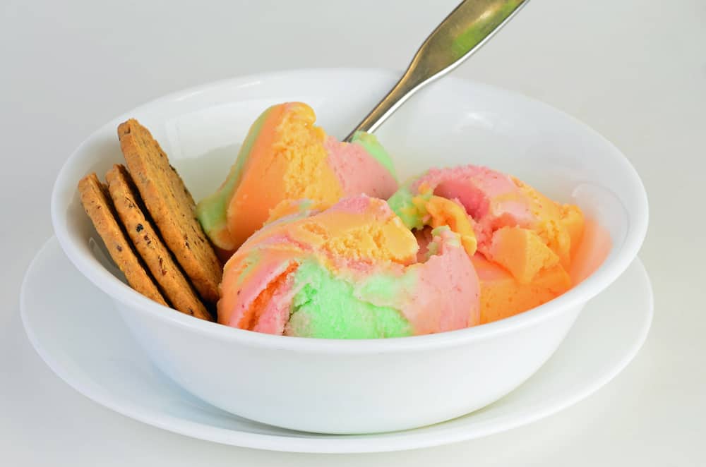 Raspberry ice cream in a bowl with crackers.