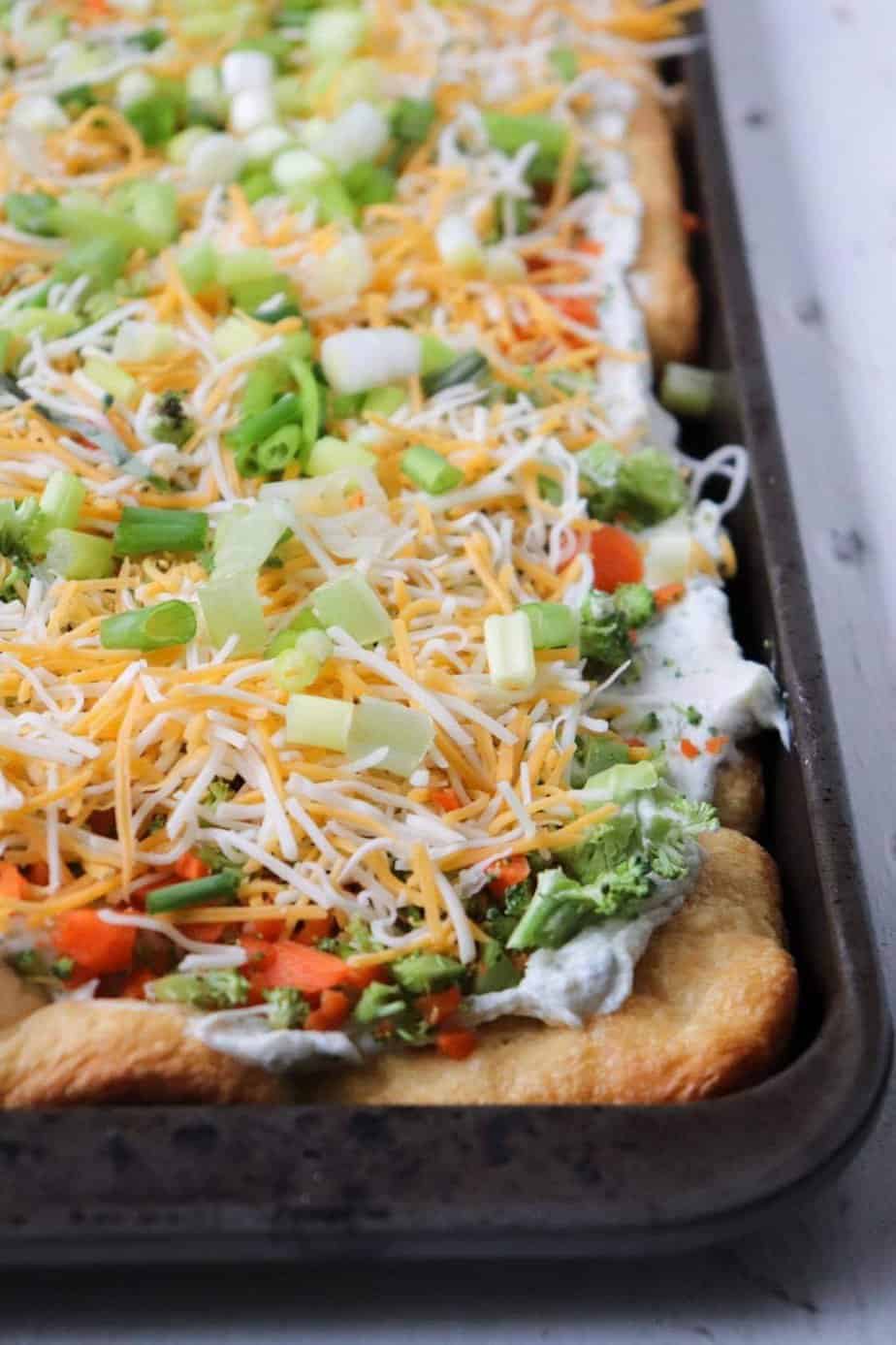 Buttery and pillowy soft crescent roll dough is topped with a cream cheese ranch sauce, veggies, and cheese.