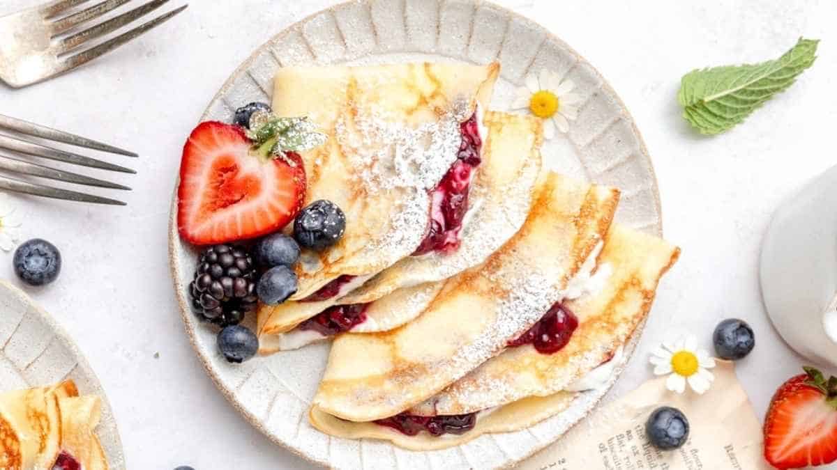 Crepes with berries and powdered sugar on a plate.