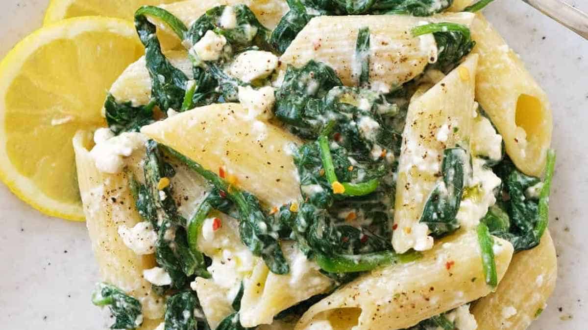 A plate of pasta with spinach and feta cheese.