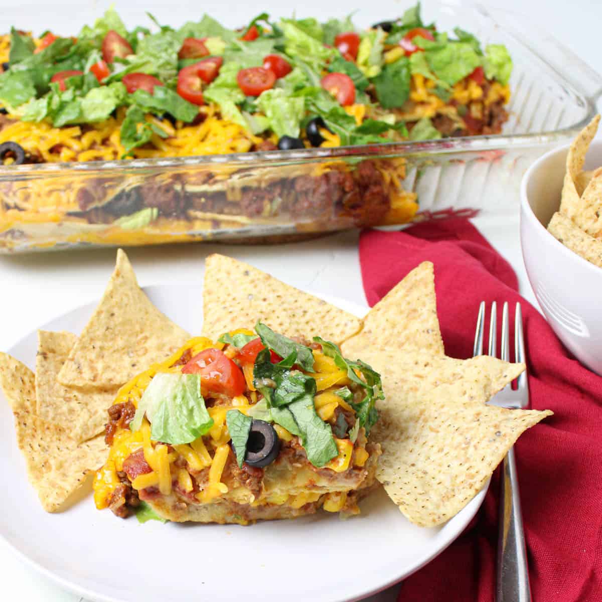 Plate of taco casserole with baking dish in the background. 
