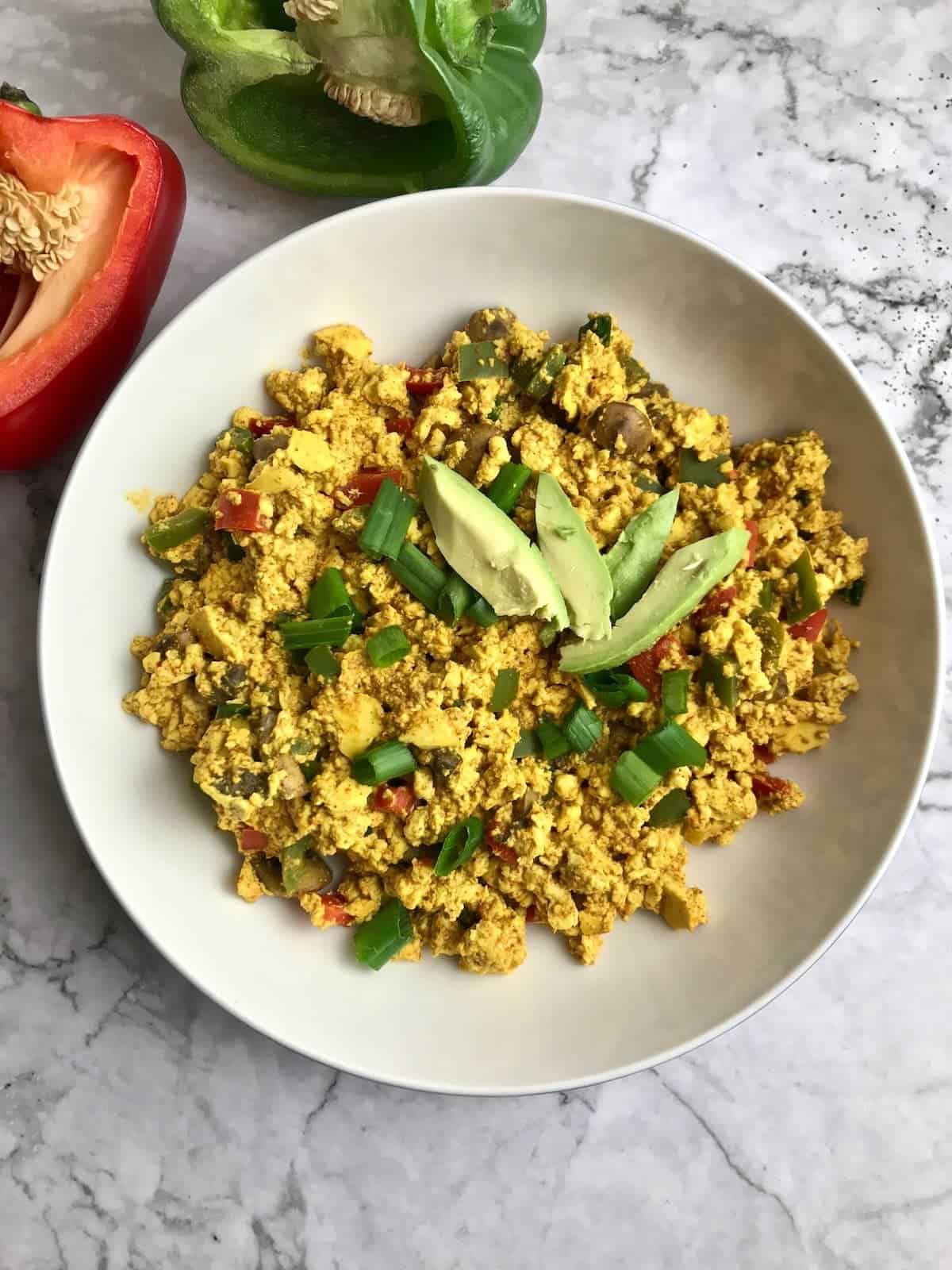 A high protein breakfast recipe consisting of scrambled eggs with avocado and peppers.