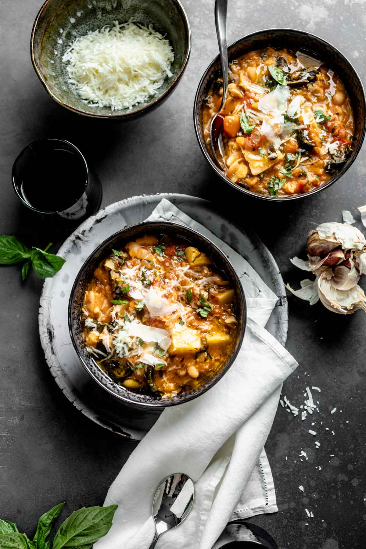 two bowls with servings of ribollita in them topped off with shredded pecorino cheese 
