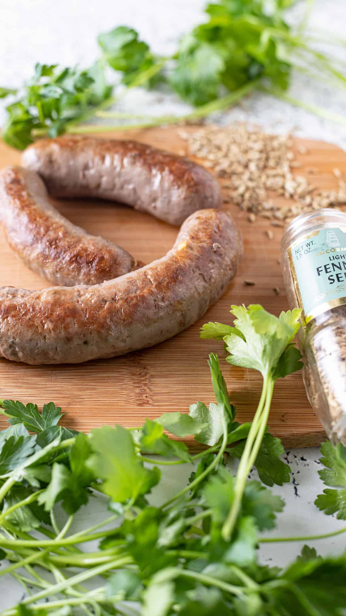 Three venison Italian sausage on wooden board with fennel. 
