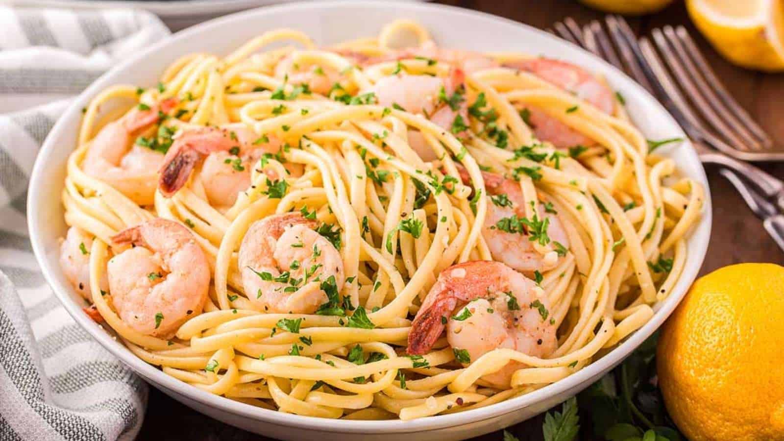 A bowl of pasta with shrimp and lemons.