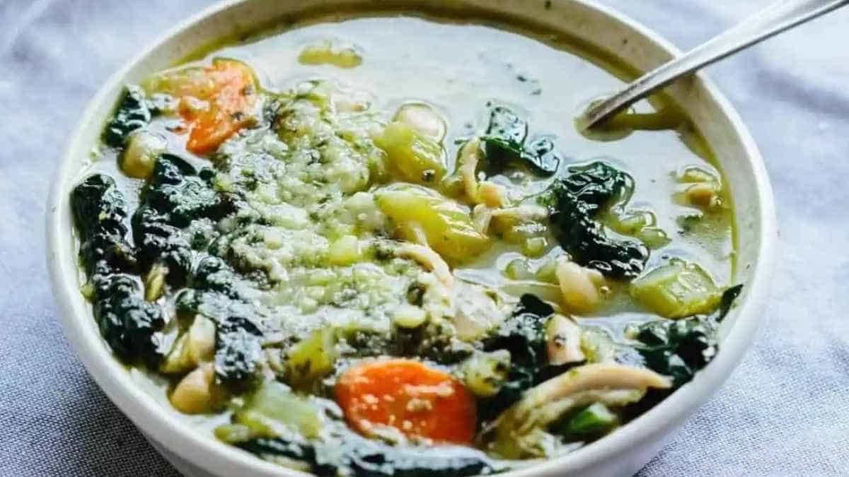 A bowl of soup with spinach and mushrooms.