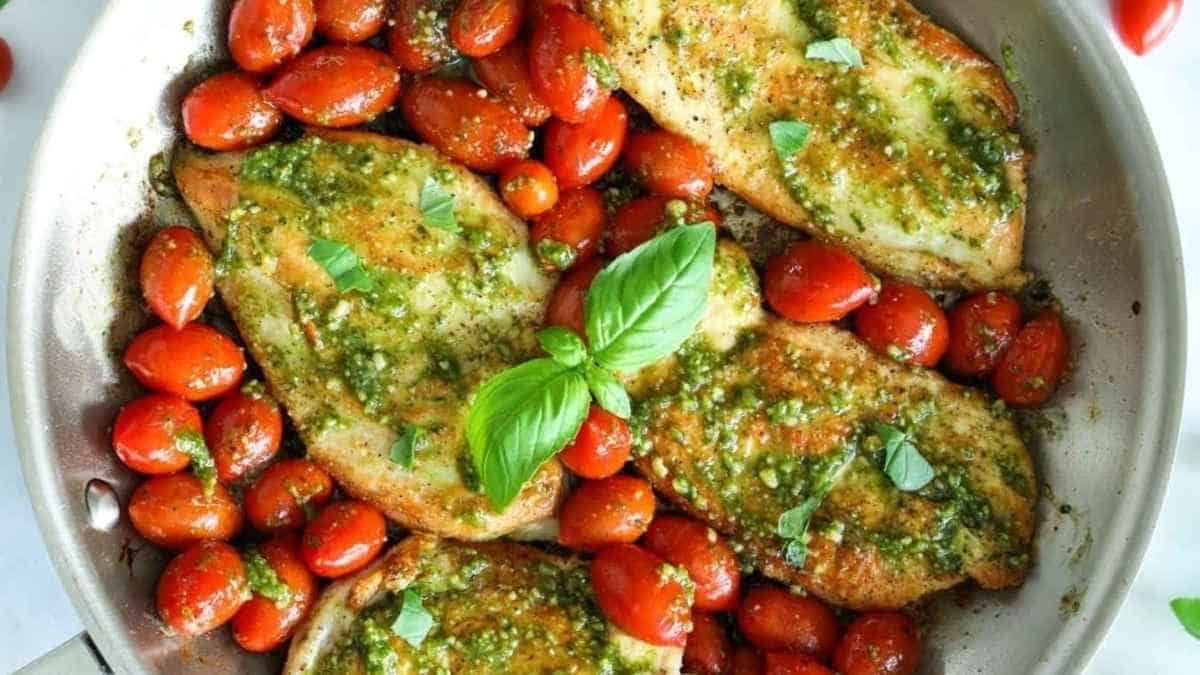 Chicken with pesto and tomatoes in a skillet.