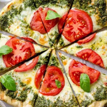 A pizza with tomatoes and basil on a wooden board.