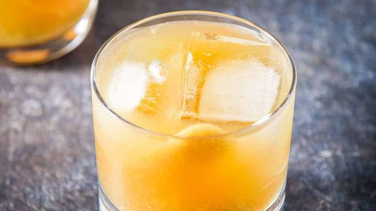 A glass of orange juice with ice and ice cubes.