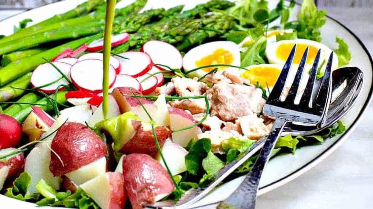 A colorful plate of salad with asparagus, radishes, eggs, and potatoes.