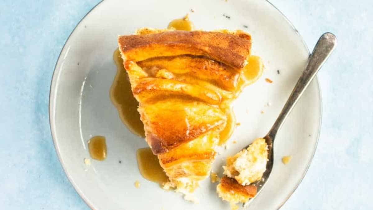 A slice of apple pie with a bite taken out, served on a plate with a fork.