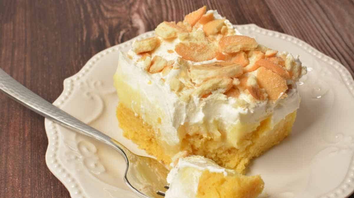 A slice of almond-topped cake on a white plate with a fork.