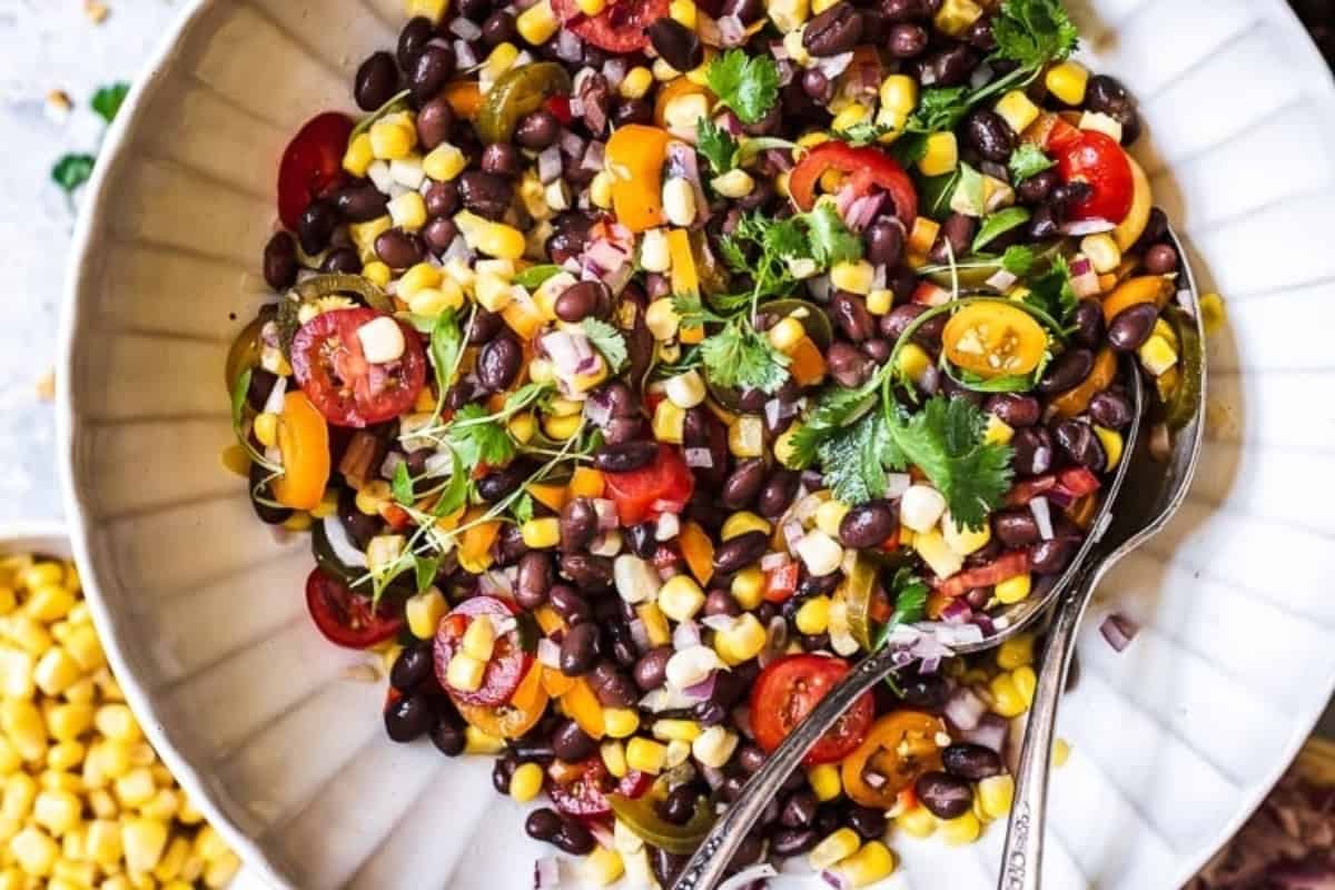 Black bean salad with tomatoes and corn in a white bowl.