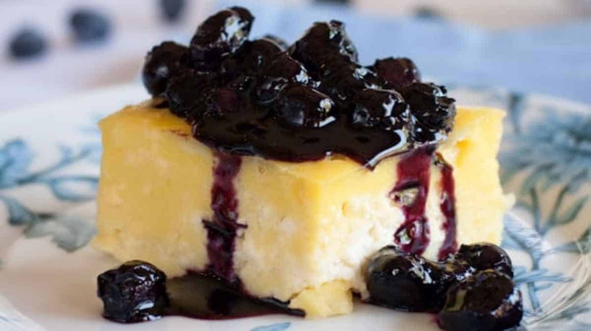 A slice of lemon cheesecake topped with blueberry compote.