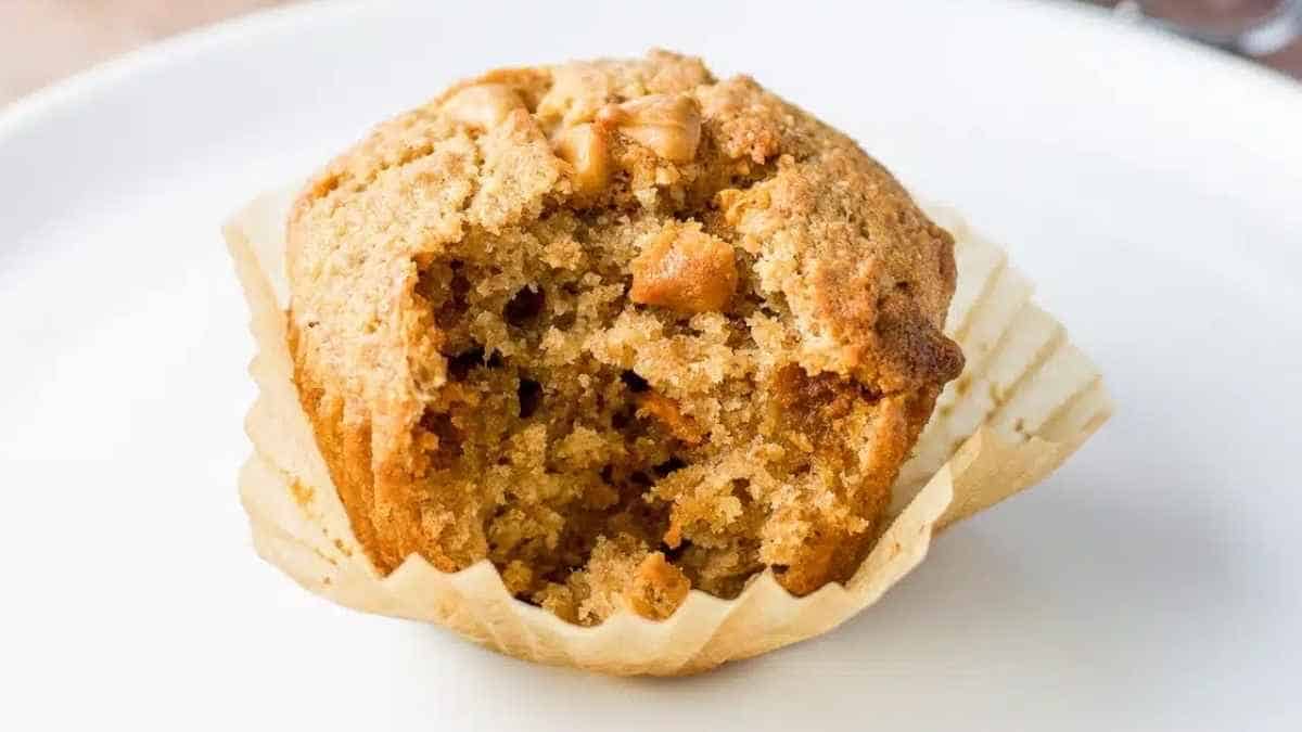 A muffin on a plate with a bite taken out of it.