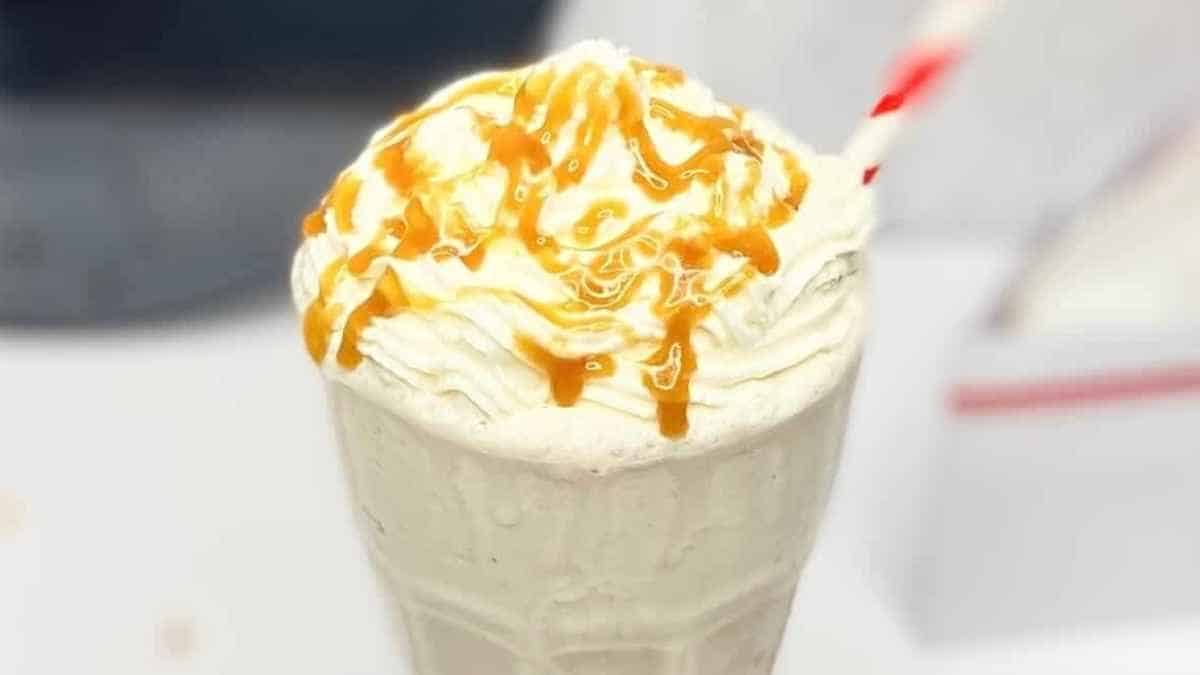 A milkshake with caramel and whipped cream.