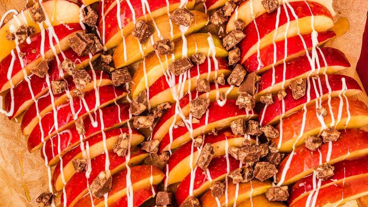Sliced apples drizzled with caramel and chocolate sauce, topped with chocolate chunks.