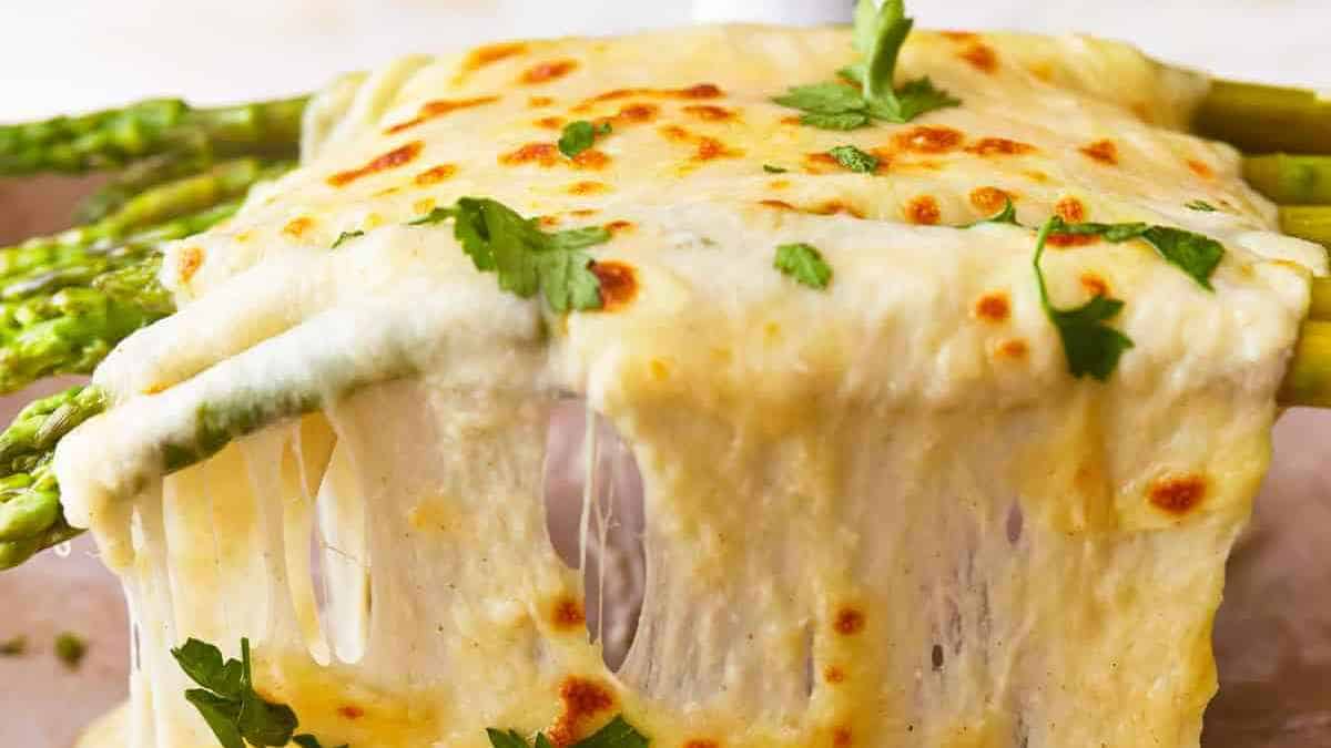 Baked asparagus under a blanket of melted cheese, garnished with parsley.