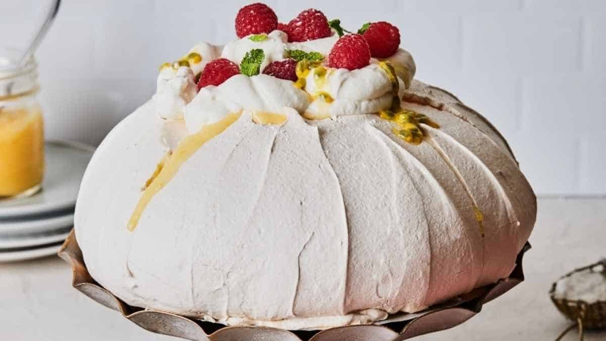 A white cake topped with raspberries and whipped cream.