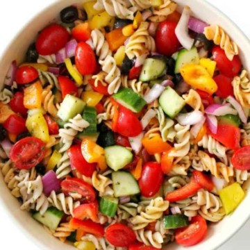 A bowl of colorful pasta salad with assorted vegetables and olives.