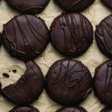 A row of chocolate covered cookies on a baking sheet.