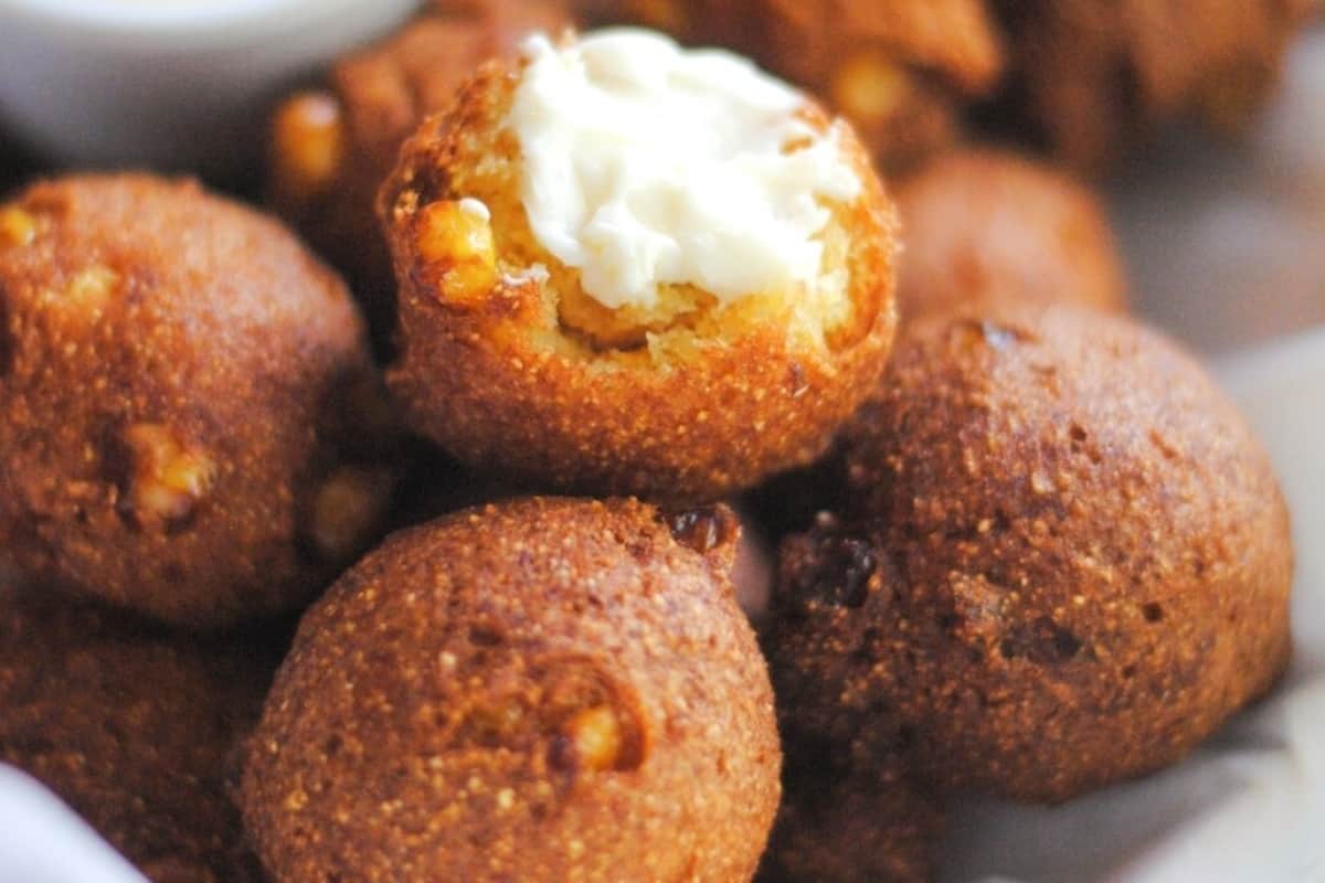 Golden brown hushpuppies served with a dollop of creamy topping.