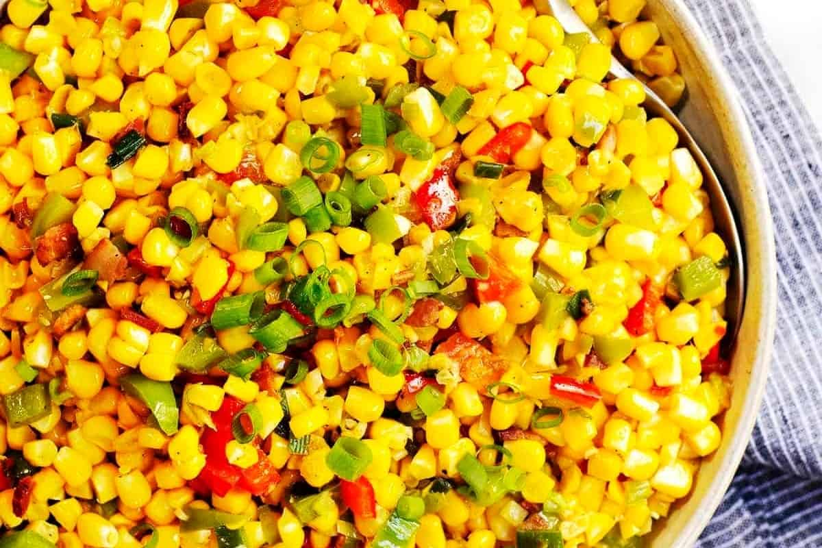 A vibrant dish of sautéed corn mixed with green onions, red peppers, and spices.