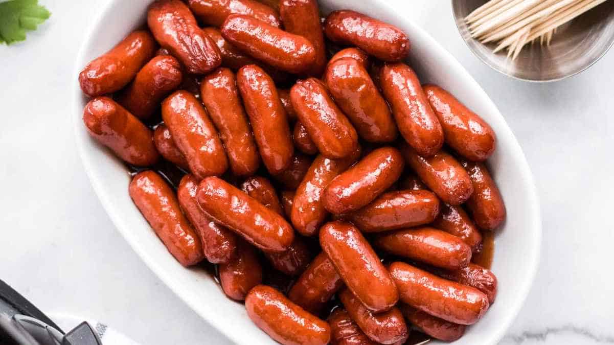 A bowl of cooked mini sausages.