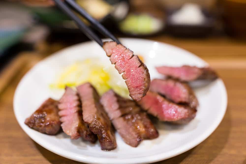 A plate of meat with chopsticks.