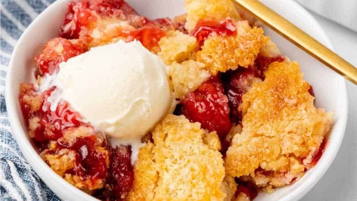 Strawberry cobbler in a bowl with ice cream.