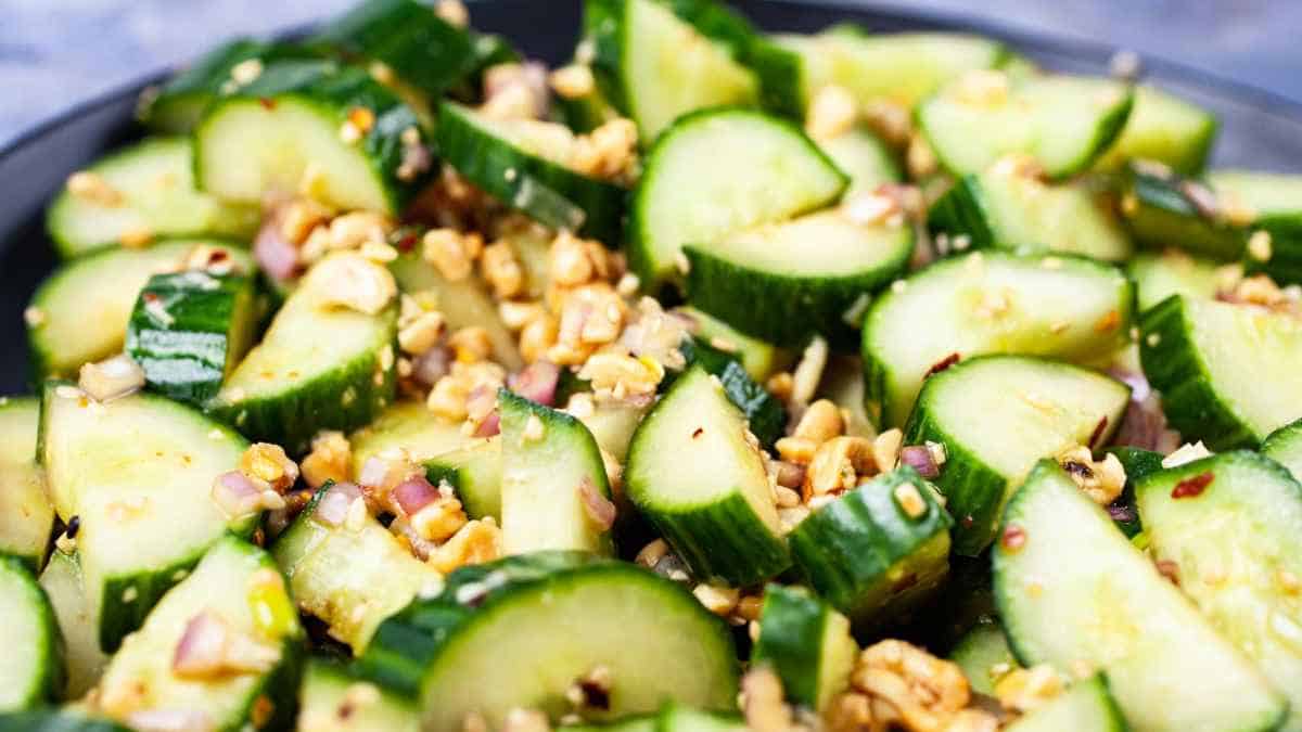 A dish of cucumber salad with chopped nuts and red onion.