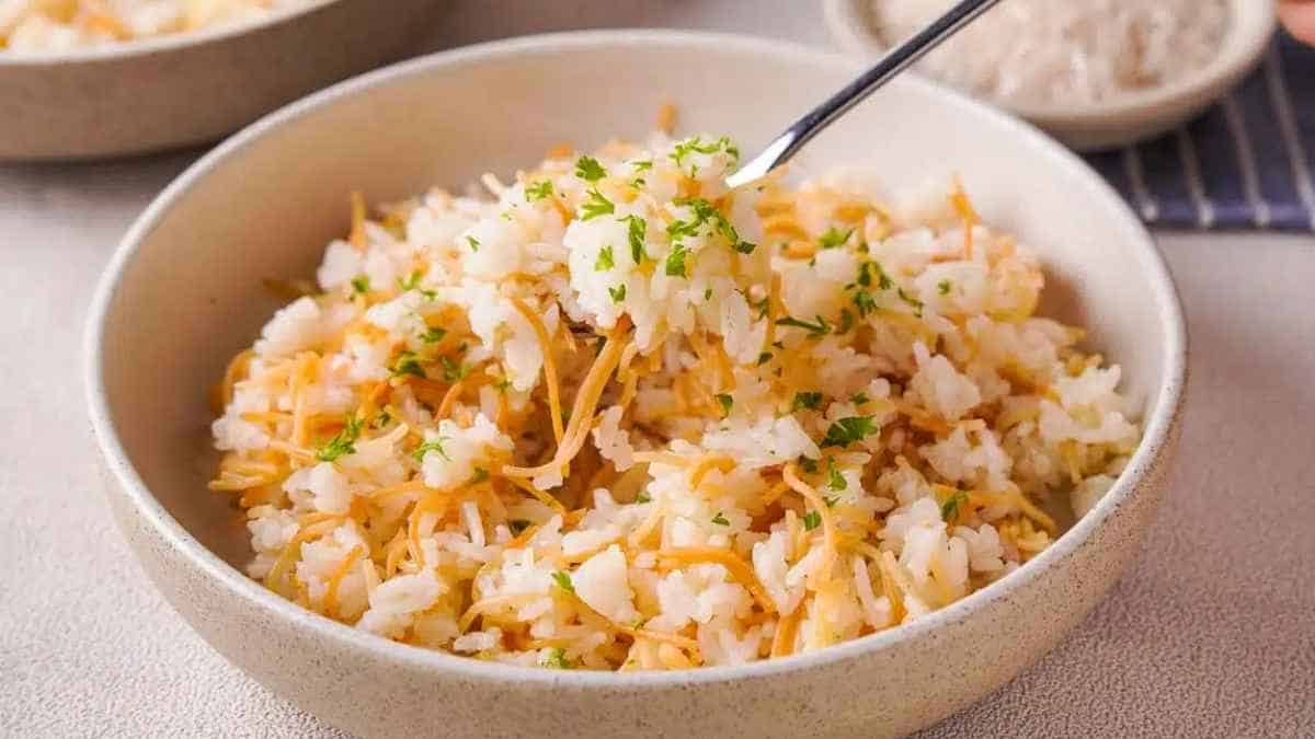 Bowl of cooked white rice garnished with herbs on a table.