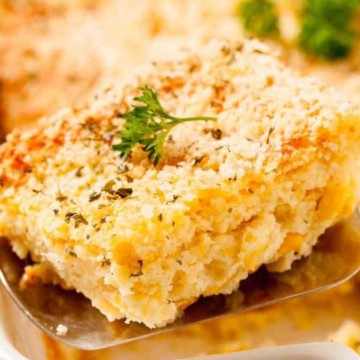 A piece of corn casserole with parsley on a spoon.