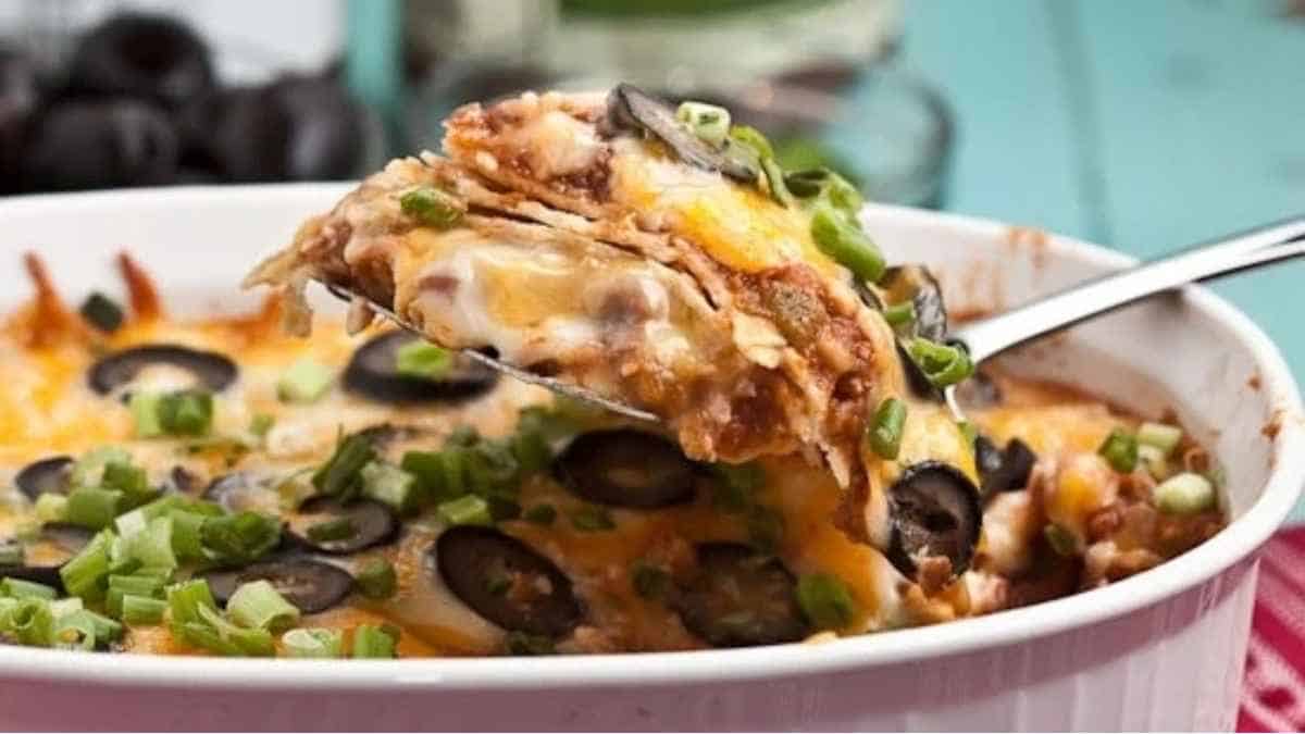 Mexican casserole in a white dish with a spoon.