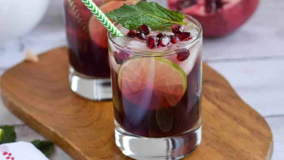 Two glasses with pomegranate juice and mint leaves.