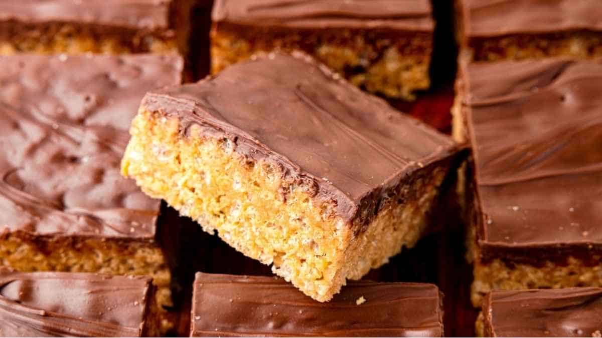 A stack of chocolate covered peanut butter bars on a wooden board.