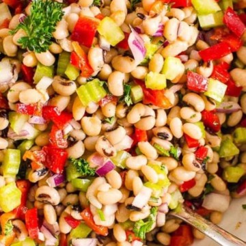 A colorful mixed bean salad with chopped vegetables in a white bowl.