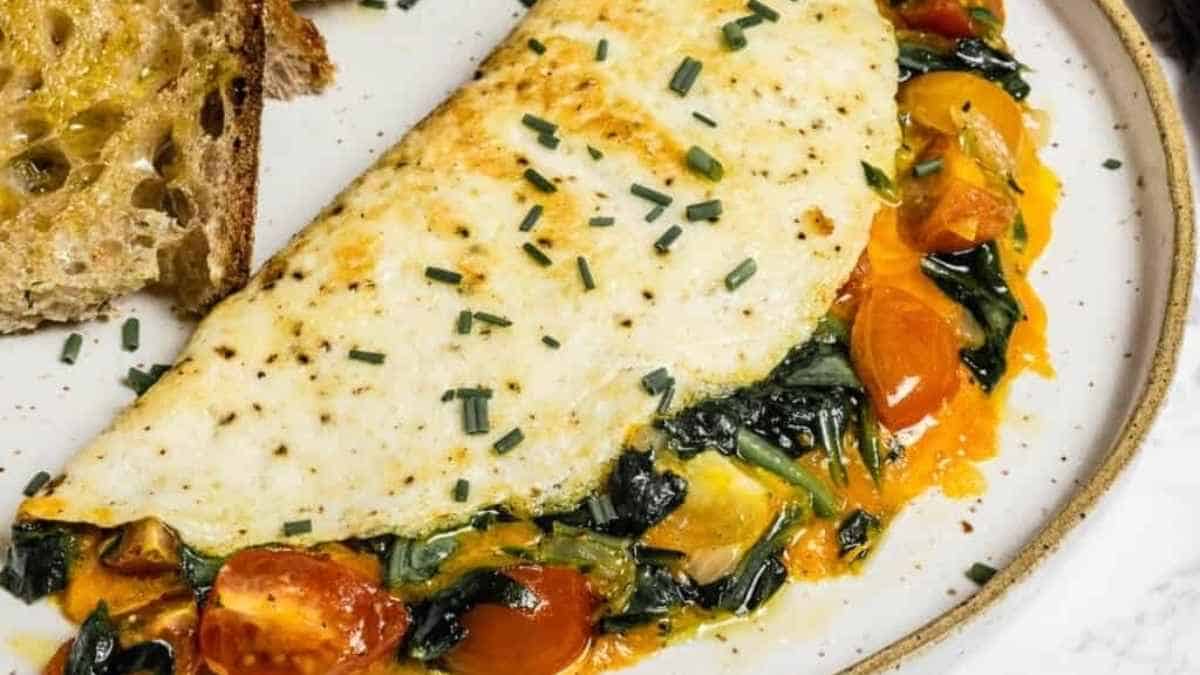 An omelet with spinach and tomatoes on a plate.